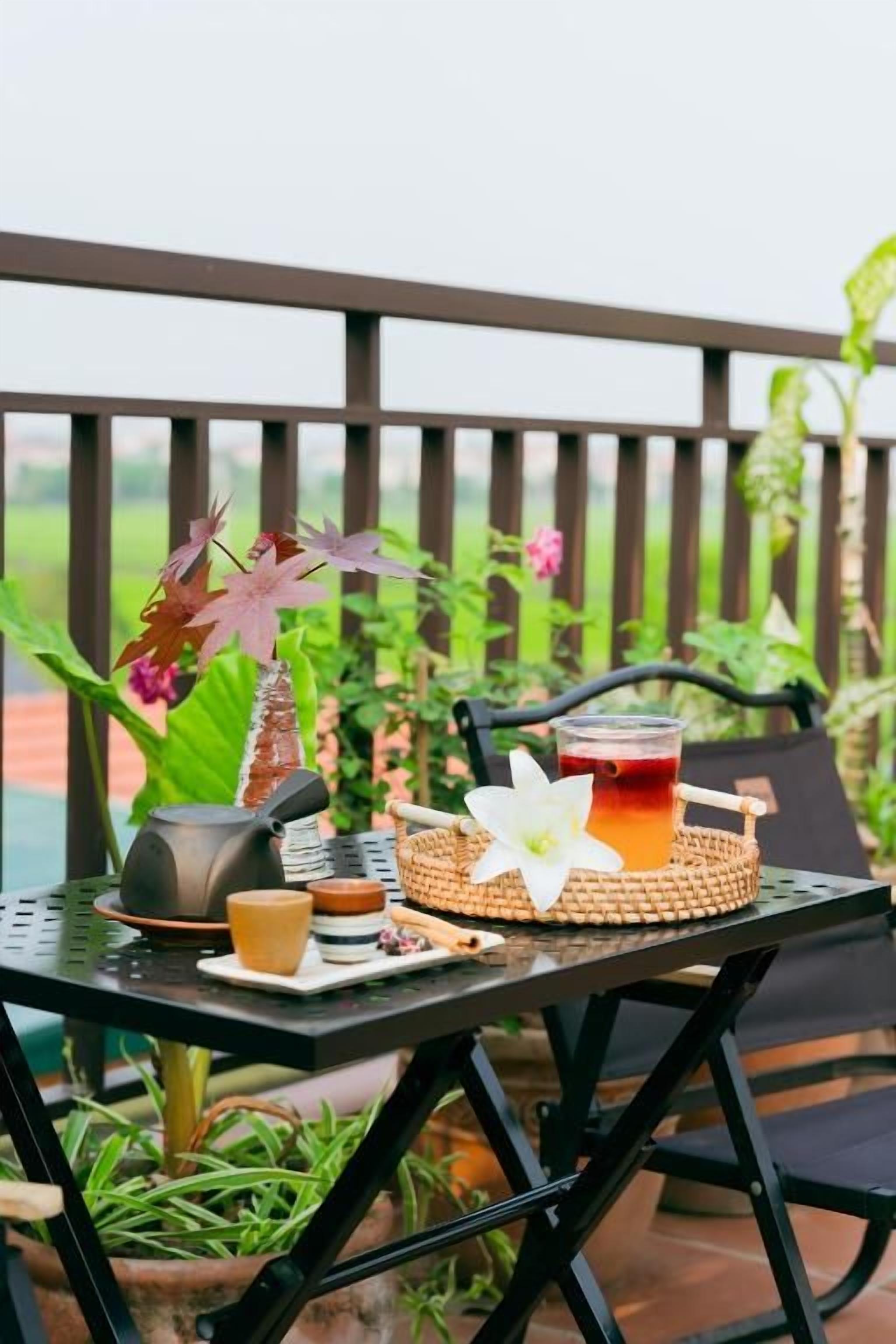 A table set outdoors with a teapot, cup, and a woven tray.