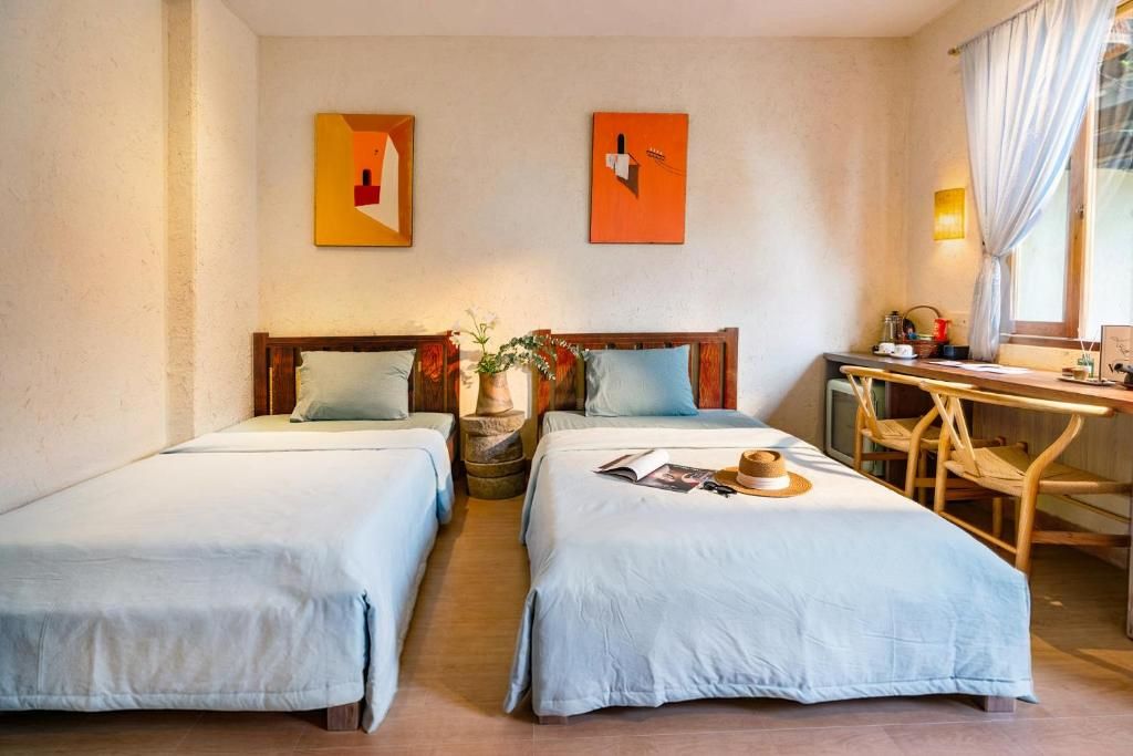A hotel room with two beds, a desk, and a chair.