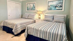 A bedroom with two beds, a nightstand with a lamp, and two framed pictures on the wall. - 8th Floor Oasis! Beautiful Gulf front views! (Panama City Beach)