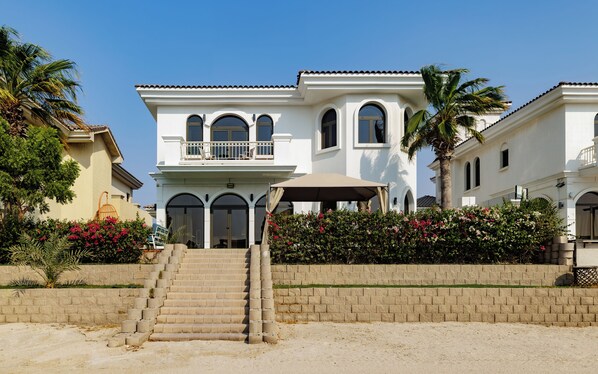 A two-story building with a balcony, a covered outdoor seating area, and a staircase leading to the entrance.