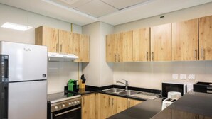 Eine moderne Küche mit Holzschränken, einem Edelstahlkühlschrank, einem Herd und einer Spüle.