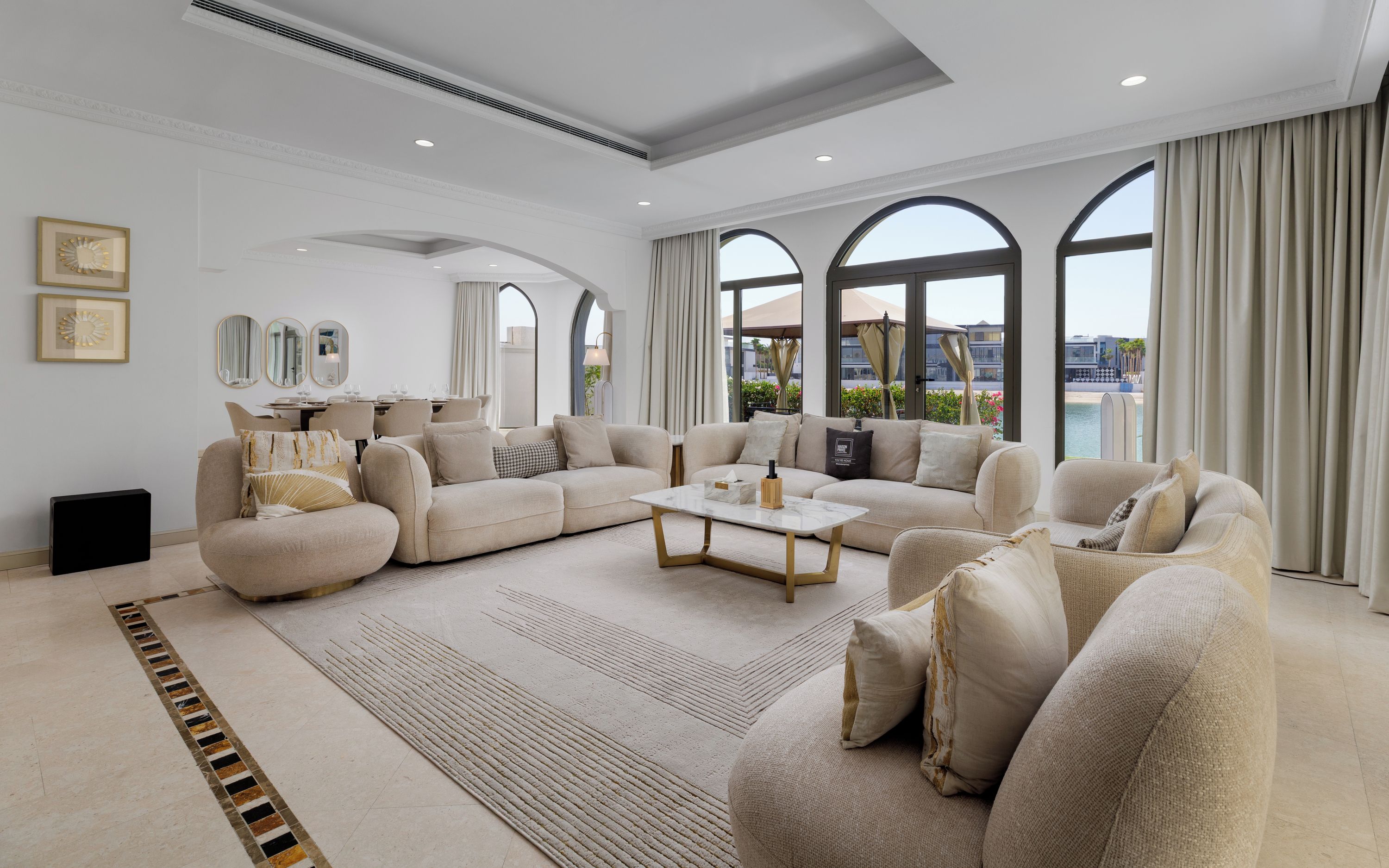 A spacious living room with a large sectional sofa, a coffee table, and a view of the outdoors through large windows.