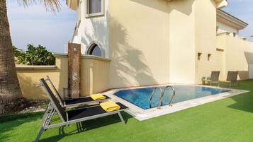 A swimming pool with a sun lounger and a small deck area.