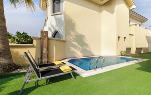 Una piscina con una tumbona y una pequeña zona de terraza.