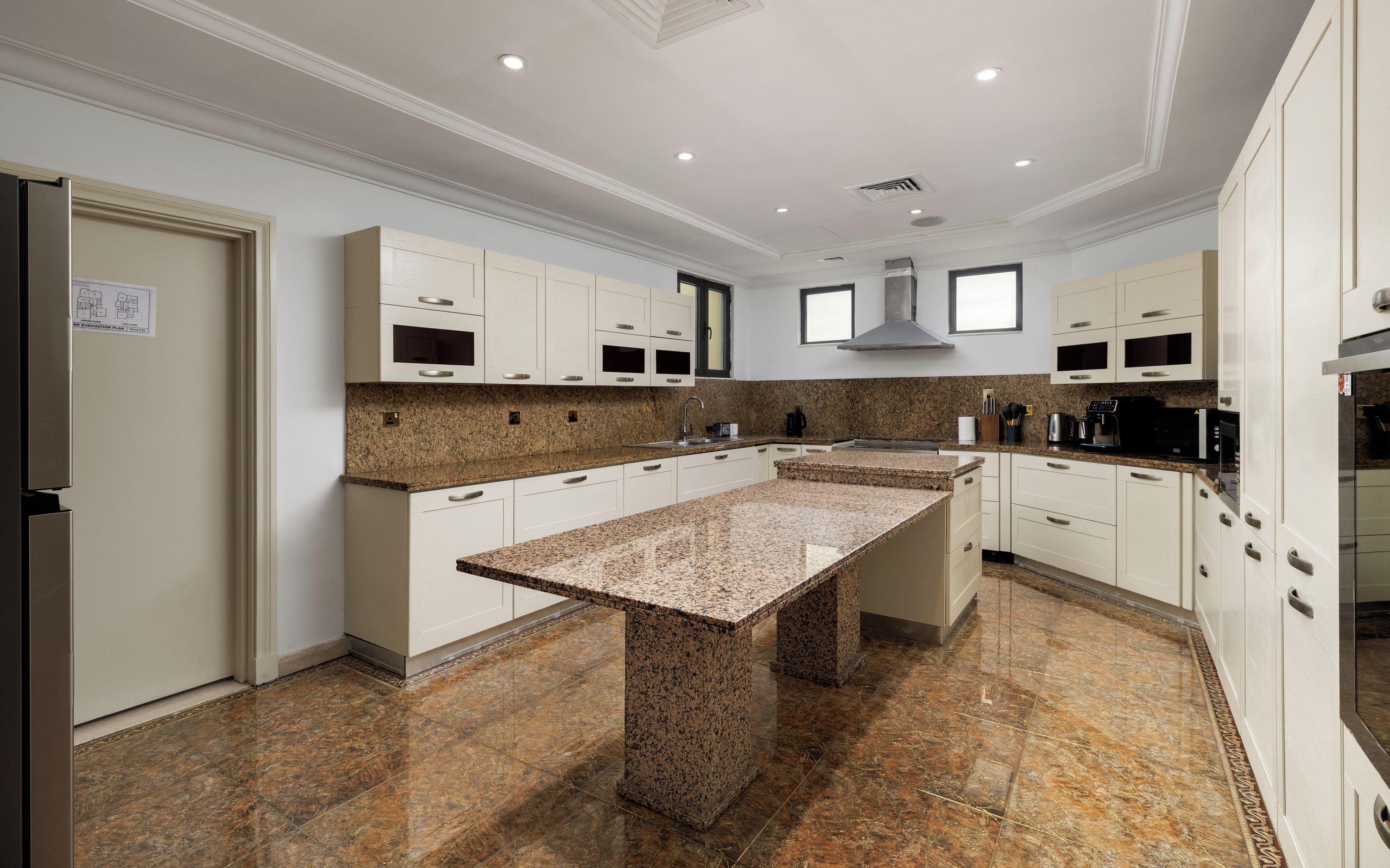 A modern kitchen with granite countertops, white cabinetry, and a central island.