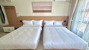 Habitación de hotel con dos camas individuales, cabecera de madera, aire acondicionado instalado en la pared y ventana con cortinas.
