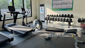Kuntosali, jossa on erilaisia kuntoilulaitteita, kuten juoksumatto, crosstrainer ja käsipainot.
