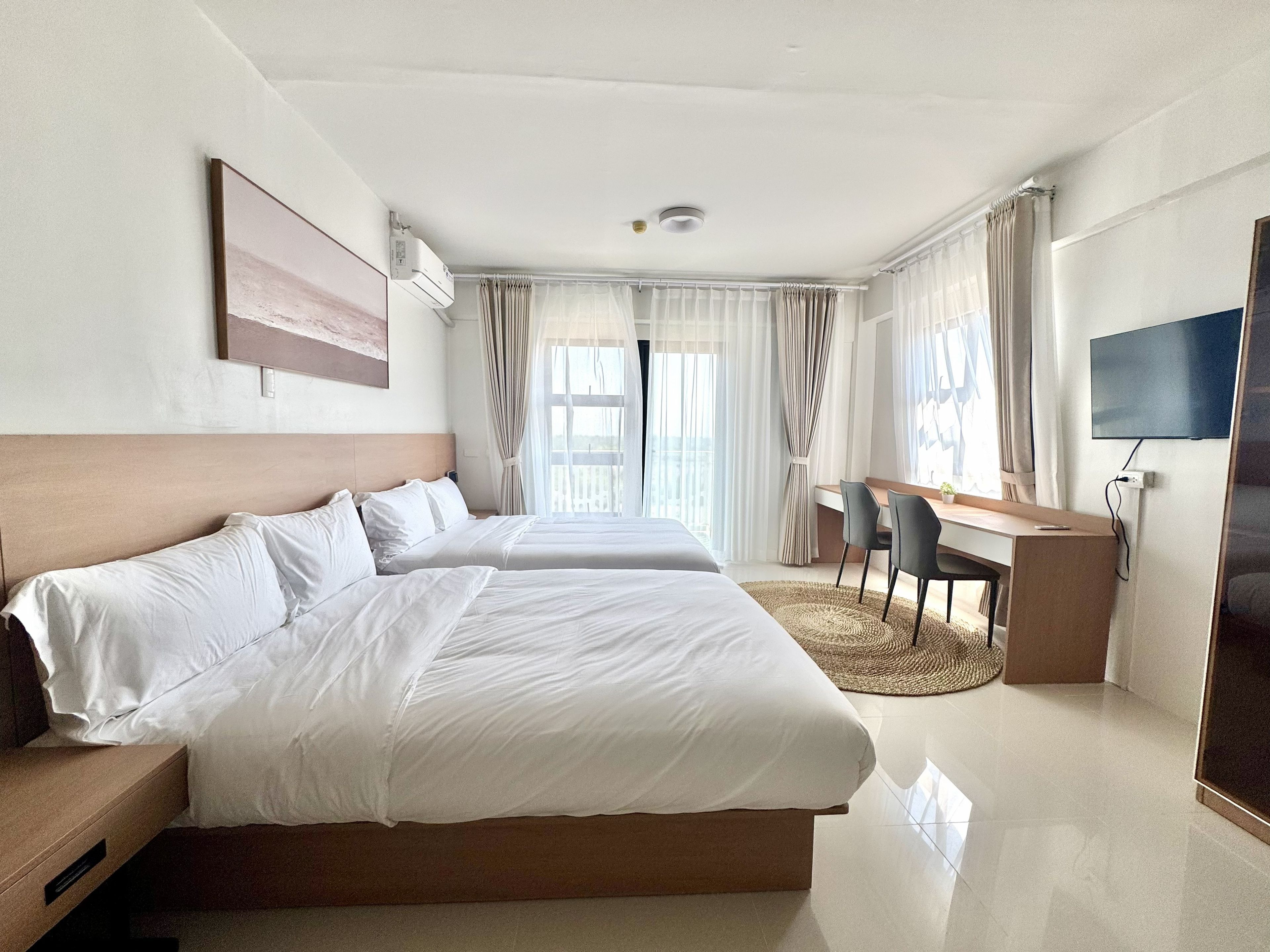 Een hotelkamer met een groot bed, een bureau, een stoel, een televisie en een raam met gordijnen.