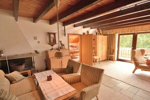 A cozy living room with a fireplace, wicker furniture, and a view through a glass door. - Devil's tail||Lenzkirch (Lenzkirch)