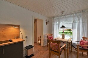 Ein Essbereich mit Tisch und Stühlen, eine Holzausstattung mit Spüle sowie ein Fenster mit Vorhängen.