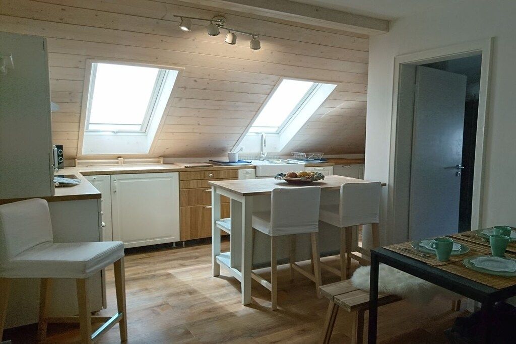 A compact kitchen with a skylight, white cabinetry, and a dining area with chairs and a table.