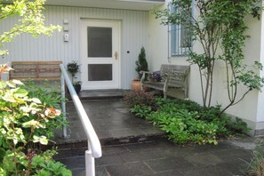 A front porch with a bench, a door, and potted plants. - Holiday apartment with 2 bedrooms (Murnau)