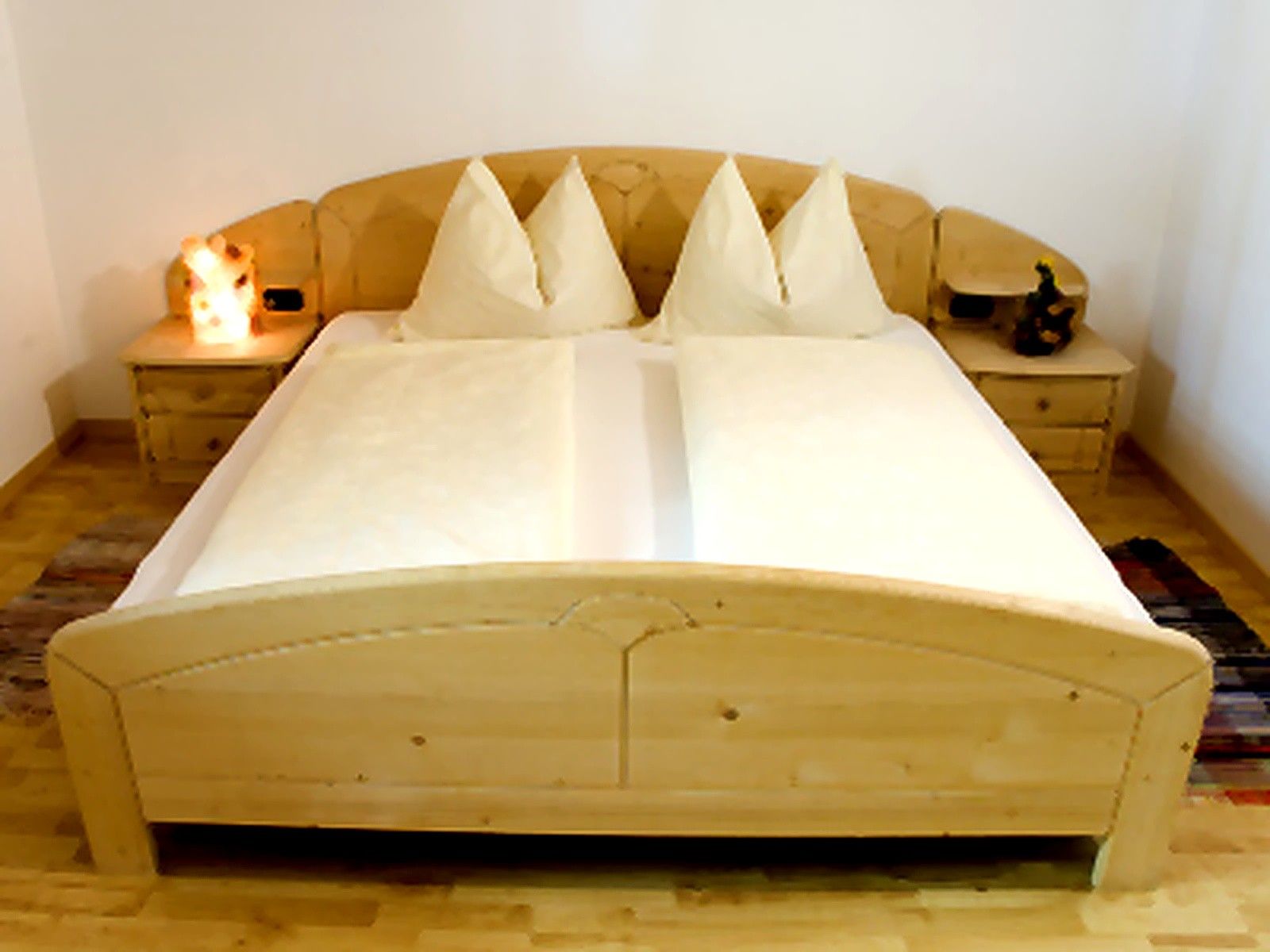 A bed with a wooden headboard and two bedside tables with lamps.