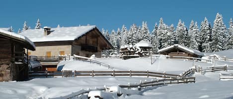 Un chalet enneigé avec des cabanes en bois et une clôture en bois.