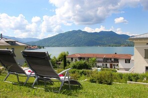 Una proprietà sul lago con due poltrone da relax, una piscina e montagne sullo sfondo.