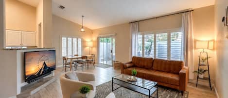 A living room with a sofa, two armchairs, a coffee table, and a TV.