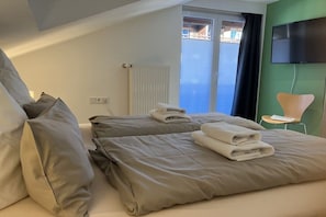 A hotel room with two beds, a television, and a window with a view. - Alpenflair holiday apartment 402 (Oberstdorf)
