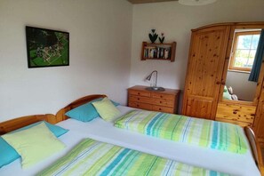 Un dormitorio con dos camas, una mesita de noche, una lámpara, un armario y un cuadro en la pared.