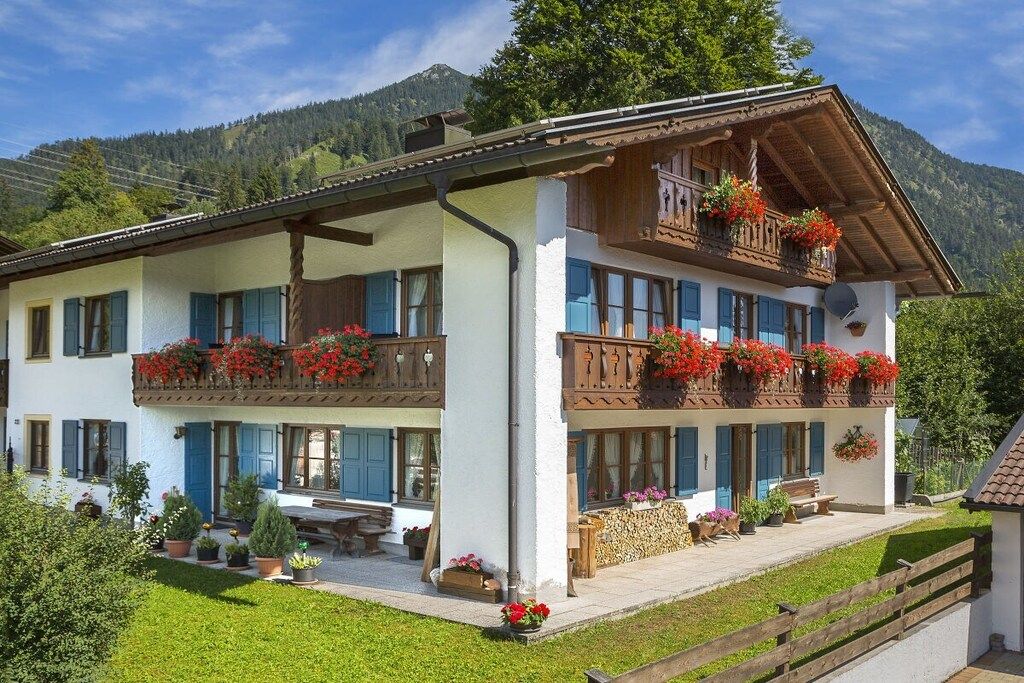 A two-story building with balconies, outdoor seating, and potted plants.
