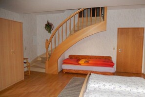 A bedroom with a wooden staircase, a bed, a sofa, and a wardrobe. - Holiday apartment with 2 bedrooms (Tambach-Dietharz)