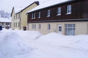 A residential building with multiple windows and a door, surrounded by snow. - Holiday apartment with 2 bedrooms (Tambach-Dietharz)