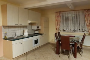 A compact kitchen with a dining area, featuring cabinets, a microwave, a coffee maker, and a dining table with chairs. - Holiday apartment with 2 bedrooms (Tambach-Dietharz)