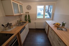 A compact kitchen with a dishwasher, a stove, a sink, and a window with a view of the outside. - Holiday apartment with 3 bedrooms (Eichstetten)