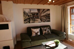 A cozy living room with a green sofa, two decorative pillows, a painting on the wall, and a window with curtains. - Alpenflair holiday apartment 317 (Oberstdorf)