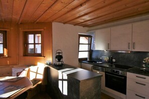 A kitchen with wooden beams, a stove, a sink, and cabinets. - Alpenflair holiday apartment 317 (Oberstdorf)