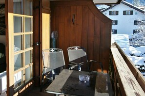 A wooden balcony with two metal chairs and a table, overlooking a snowy landscape. - Alpenflair holiday apartment 317 (Oberstdorf)