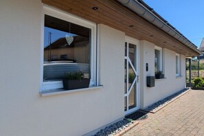 A building with large windows, a wooden roof, and a paved walkway. - Holiday home in Osburg with swimming pool (Osburg)