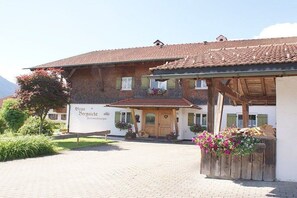 En traditionell byggnad med ett tak täckt av tegelpannor, en träveranda och en skylt som visar att det är ett hotell.