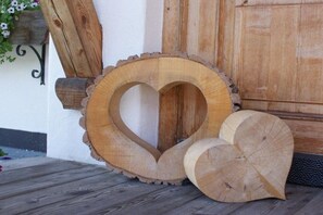 Ein herzförmiges Holzschild auf einem Holzboden, im Hintergrund eine Holztür und eine weiße Wand.