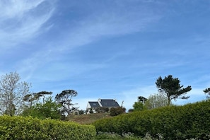 Ein Haus auf einem Hügel, strahlend blauer Himmel.