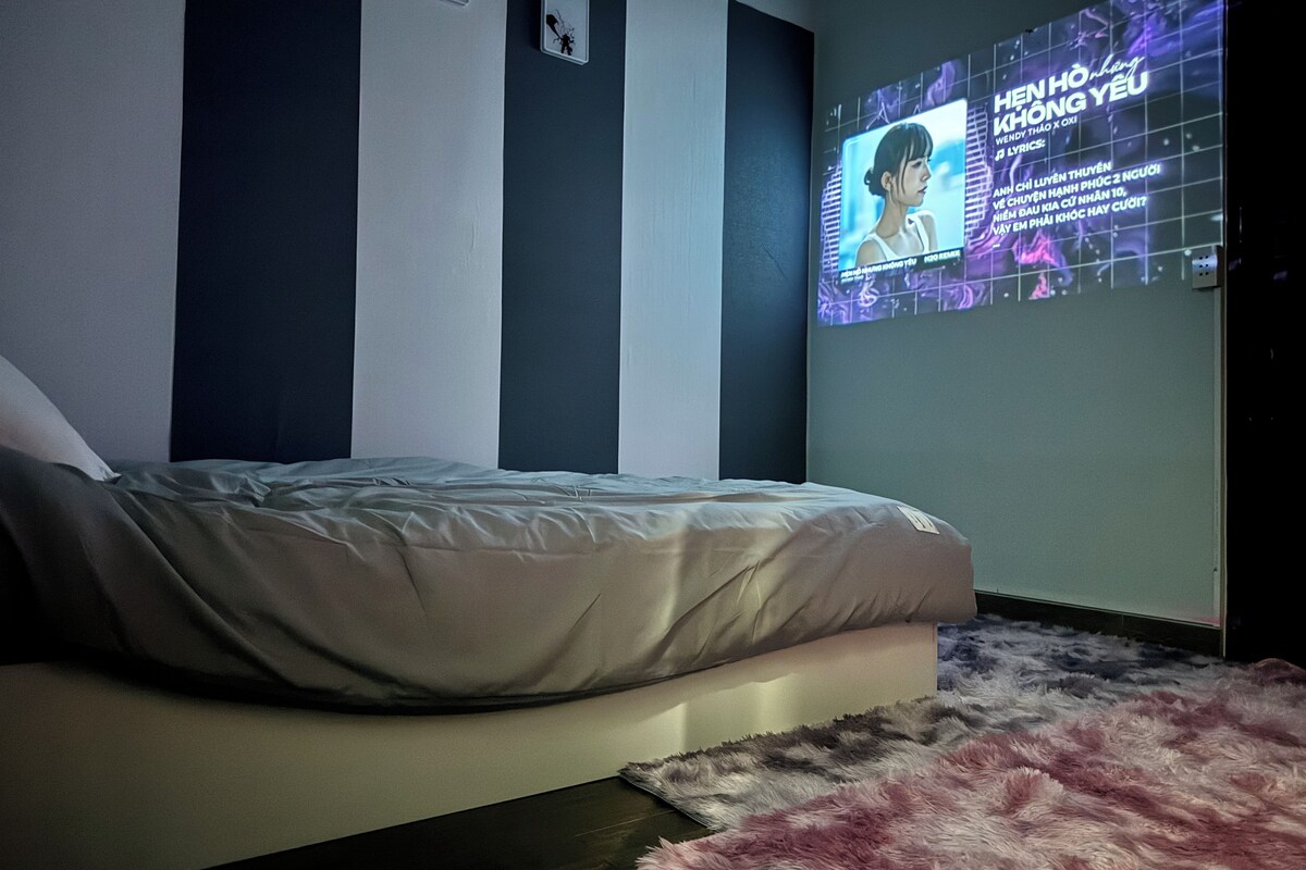Un dormitorio con cama, televisor montado en la pared y una alfombra mullida.
