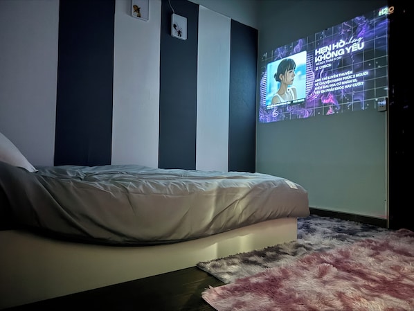 Un dormitorio con cama, televisor montado en la pared y una alfombra mullida.