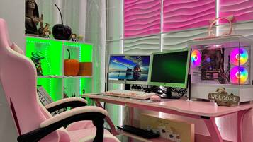 Ein Zimmer mit einem pinkfarbenen Gaming-Stuhl, einem Schreibtisch mit Computerarbeitsplatz und einem weichen, pinkfarbenen Teppich.