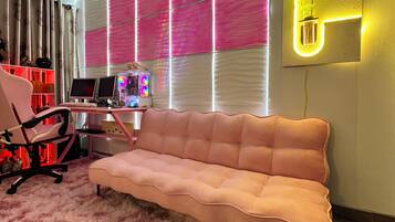 Una sala de estar moderna con un sofá rosa, un escritorio con una computadora y un aplique de pared.