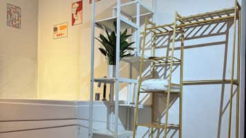 Una habitación con un sofá blanco, un estante blanco, una escalera de madera y una planta en maceta.