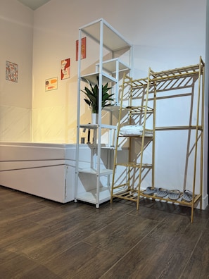 A room with a white sofa, a white shelving unit, a wooden ladder, and a potted plant.