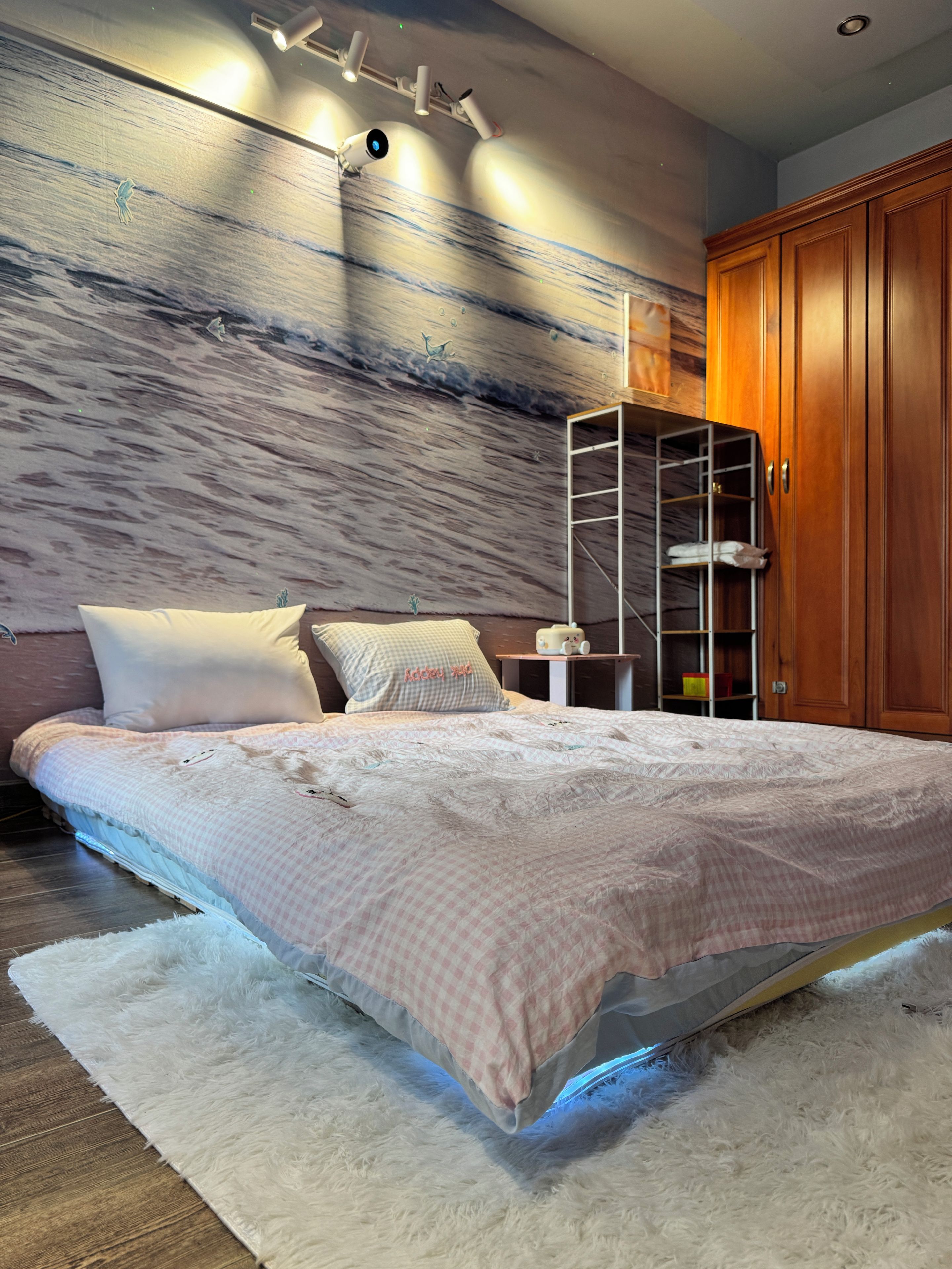 Ein Schlafzimmer mit einem Bett, einem weißen, flauschigen Teppich, einem Holzschrank und einer Wand mit einer strukturierten Wandmalerei.