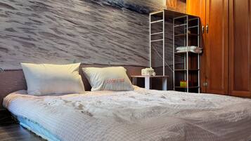 Ein Schlafzimmer mit einem Bett, einem weißen, flauschigen Teppich, einem Holzschrank und einer Wand mit einer strukturierten Wandmalerei.