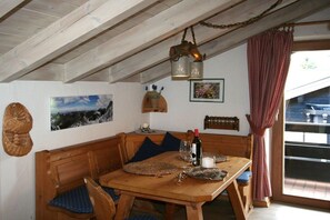 A wooden dining table with chairs, a bench, and a hanging light fixture. - Alpenflair Holiday Apartment 216 (Oberstdorf)