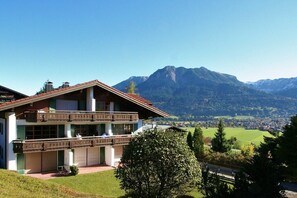 Un immeuble de deux étages doté d’un balcon, situé sur un site offrant une vue sur les montagnes.