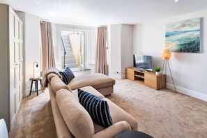 Ein modernes Wohnzimmer mit einer Couch, einem Fernseher und einem Gemälde an der Wand.