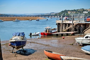 A riverside scene with boats docked along the shore and a bridge in the background. - Seaside Escape (Teignmouth)