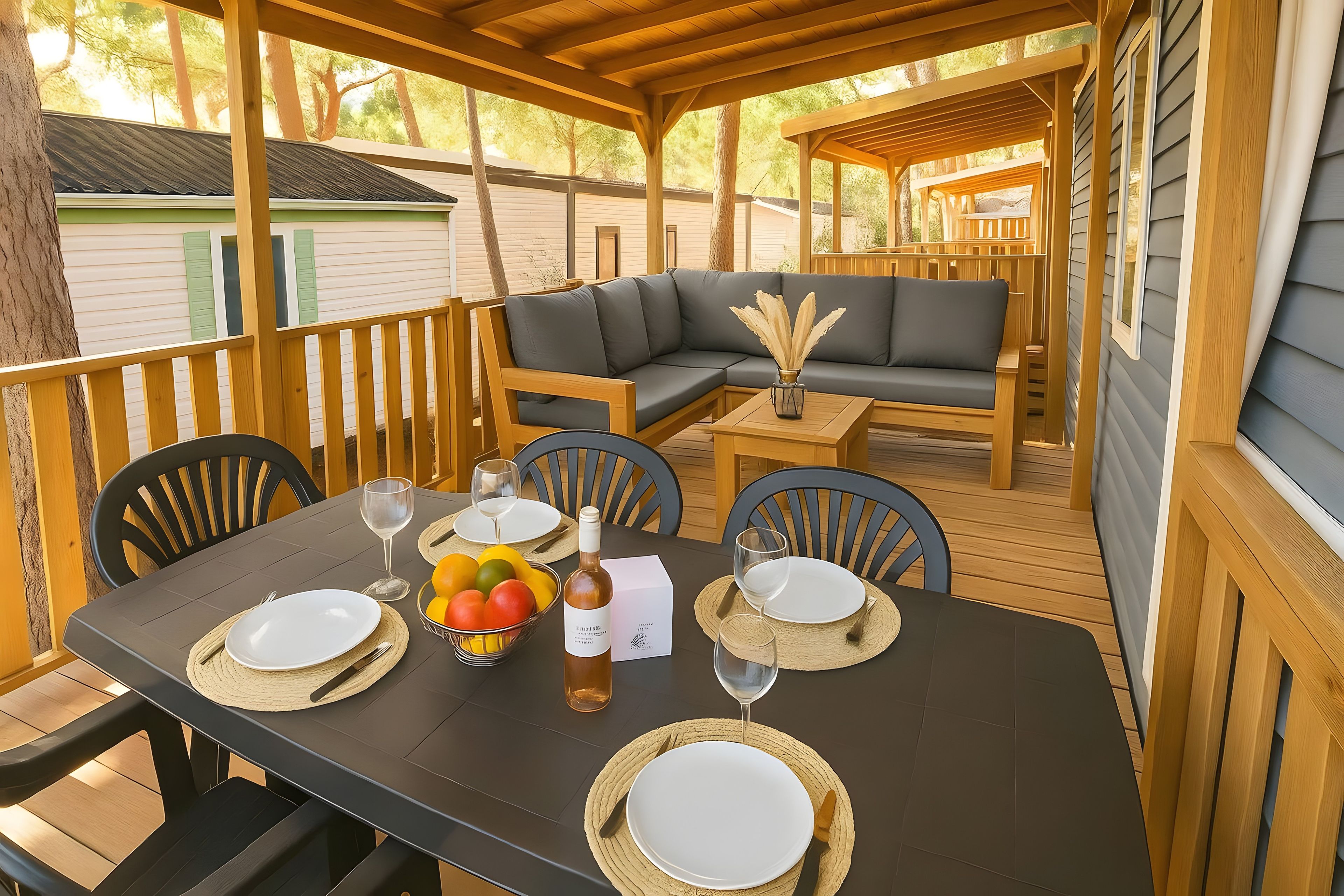 Une terrasse extérieure avec une table à manger pour quatre personnes, entourée de chaises en bois et d’un canapé.