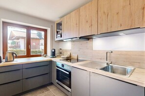 Eine moderne Küche mit eingebautem Ofen, einer Edelstahl-Spüle und Holzschränken.