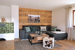 A living room with a grey sofa, a coffee table, and a cow-themed ottoman. - Alpenflair holiday apartment 312 (Oberstdorf)