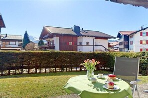 A table set outdoors with a tablecloth, a vase with flowers, and a plate with a dessert. - Alpenflair holiday apartment 312 (Oberstdorf)